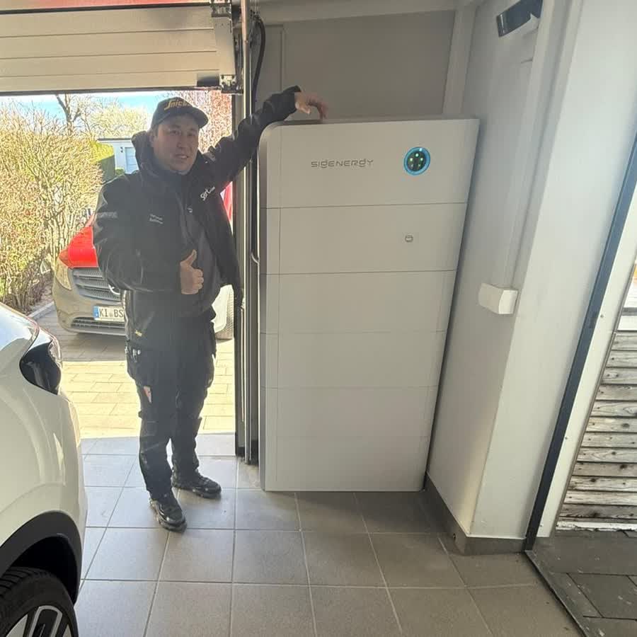 BSH-Monteur mit Daumen hoch vor installiertem Sigenergy-Stromspeicher in einer Kundengarage in Kiel
