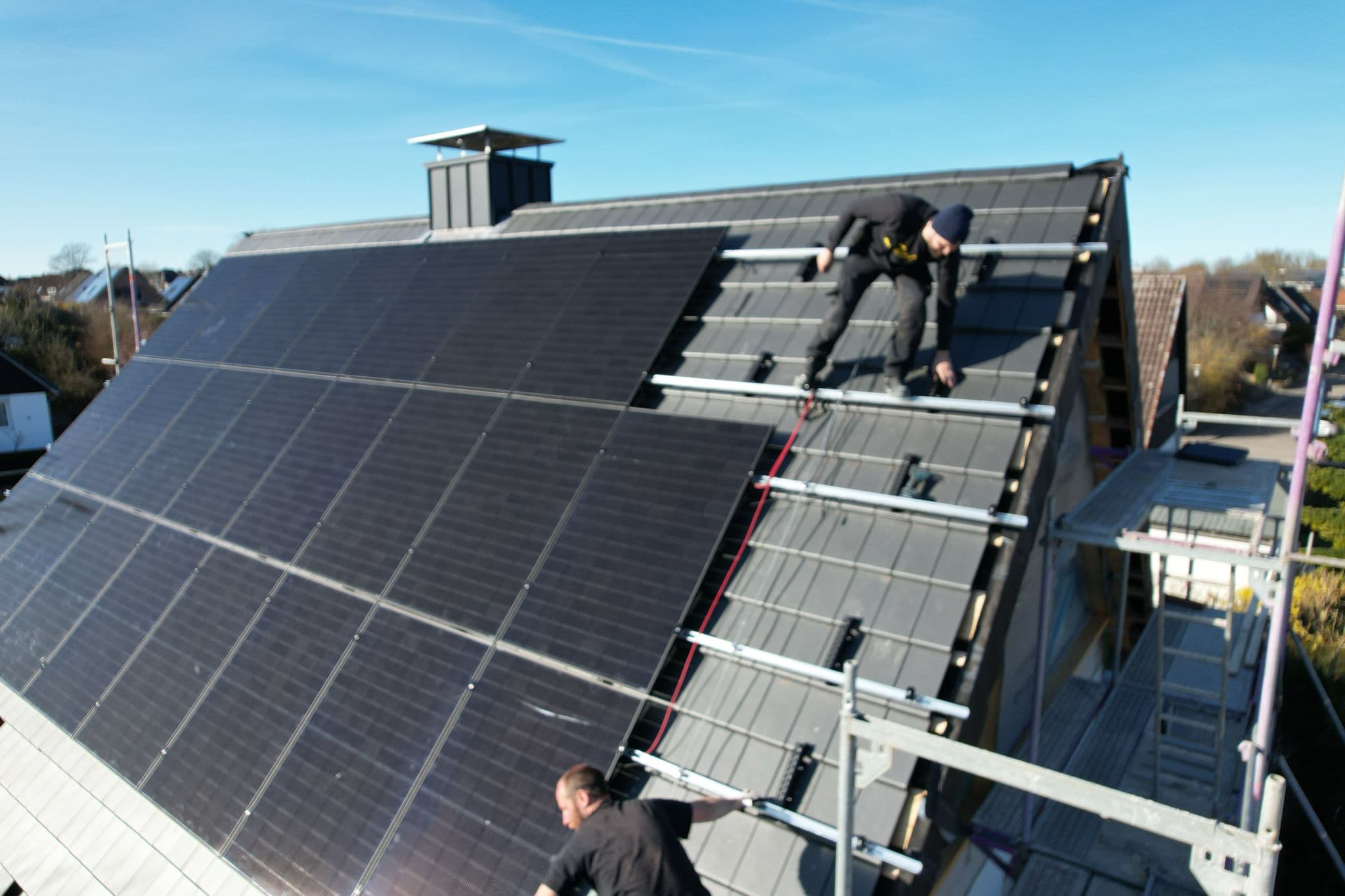 Zwei BSH-Monteure montieren Solarmodule auf einem Steildach in Schleswig-Holstein